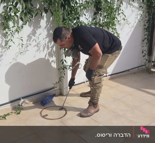 אדם מבצע הדברה עם ציוד מקצועי בחצר